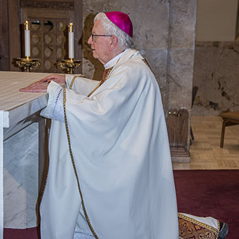 Bishop Ricken kneeling